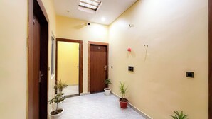 Um corredor com duas portas, plantas em vasos e um lustre.