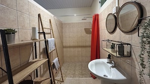 Ein kleines Badezimmer mit Dusche, Waschbecken, Spiegel und Handtuchhalter.