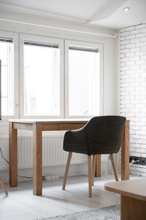 Une pièce avec une table en bois, une chaise rembourrée de couleur gris foncé et un mur en briques blanches.