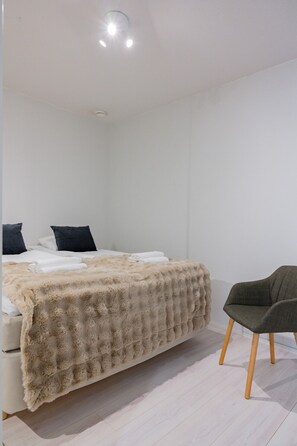 Une chambre à coucher avec un lit, des oreillers, une chaise et un luminaire au plafond.