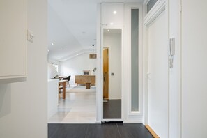 A modern interior with a dining area, kitchen, and a hallway leading to a door. - Taiga Penthouse, Private Sauna By Lapland Host (Rovaniemi)