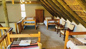 Une chambre mansardée au décor rustique, avec des meubles en bois, une grande armoire et un plafond en pente.