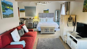 Une chambre d’hôtel avec un lit, un canapé rouge, une télévision et un bureau.