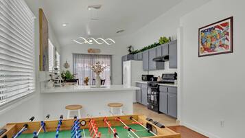 Een moderne keuken met grijze kastjes, een centraal eiland en een tafelvoetbal in de voorgrond.