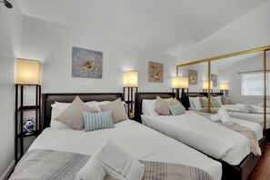 Ein Hotelzimmer mit zwei Betten, jeweils mit Kopfteil, Nachttischlampen und Zierteichen.