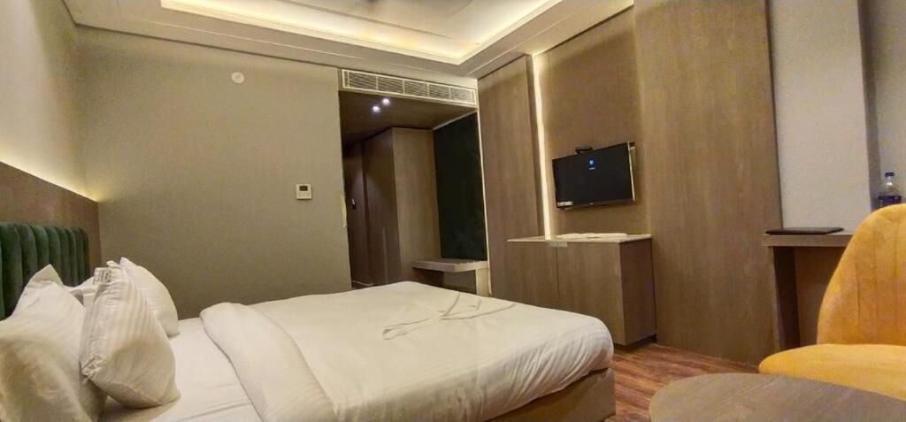 Una camera d'albergo con un letto, una televisione, un angolo salotto e un tavolino.