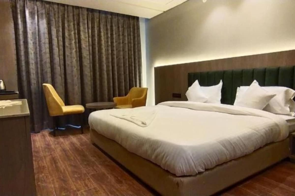 Een hotelkamer met een groot bed, een stoel, een tafeltje en een televisie.