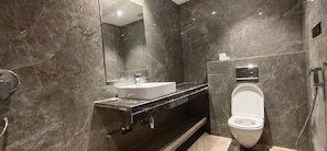 Een moderne badkamer met een marmeren wand, een wit wastafelmeubel en een toilet.