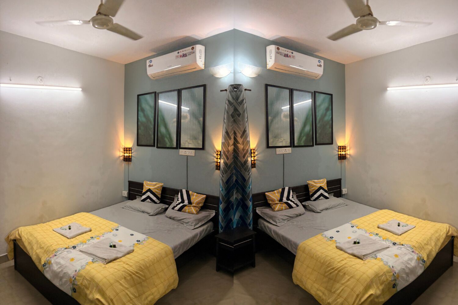 A mirrored room with two beds, air conditioning units, wall-mounted lights, and a central decorative column.