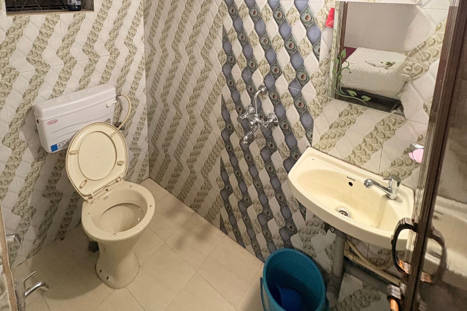 A bathroom with a toilet, sink, and patterned walls.