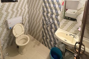 A bathroom with a toilet, sink, and patterned walls. - D'souza Brother Guest House Baga Goa (Arpora)