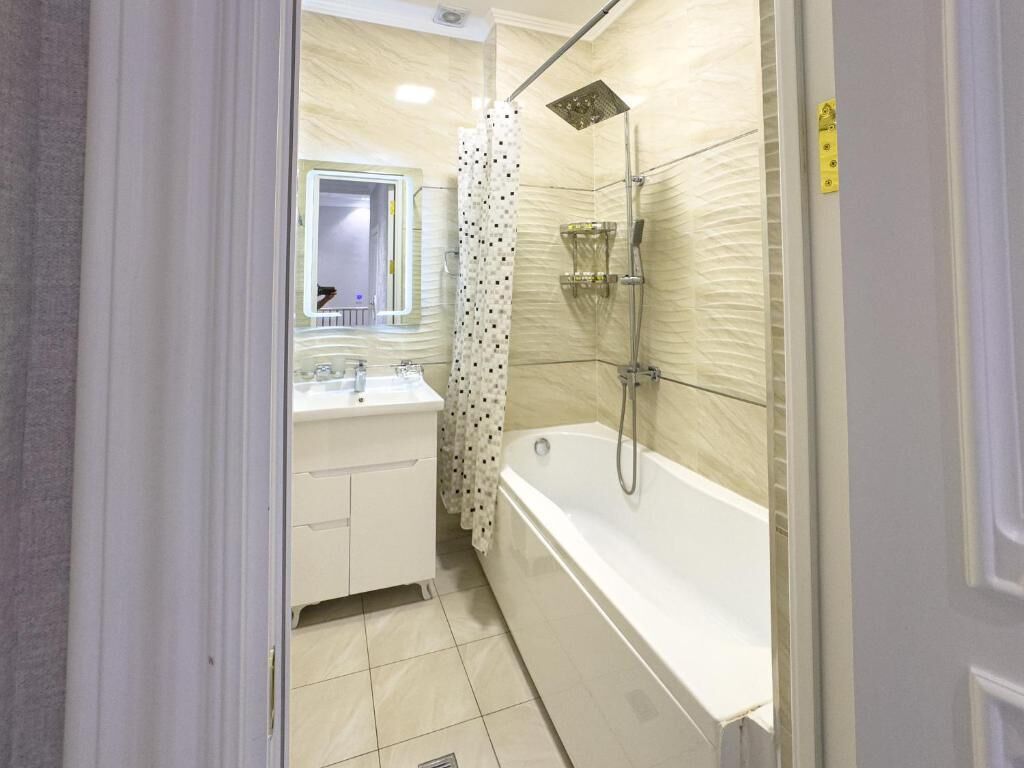 A bathroom with a bathtub, shower, and a mirror.