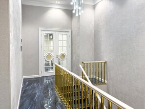 Una escalera con barandilla dorada y una puerta blanca al fondo.