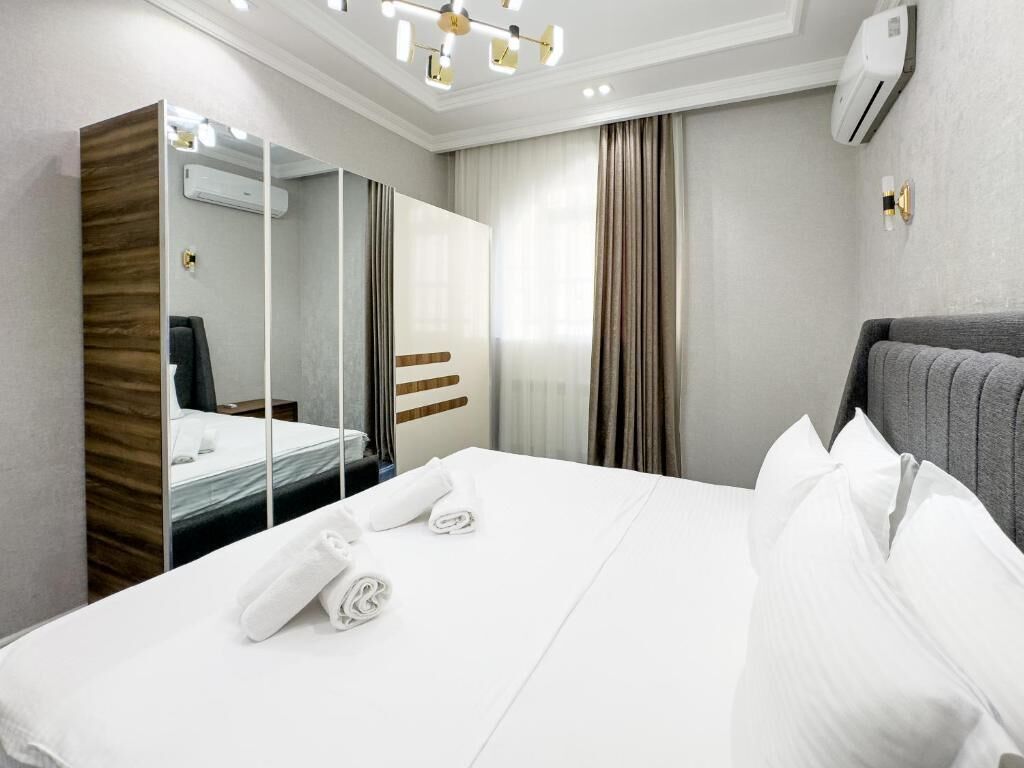 A hotel room with a large bed, a mirror, a wardrobe, and a ceiling light fixture.