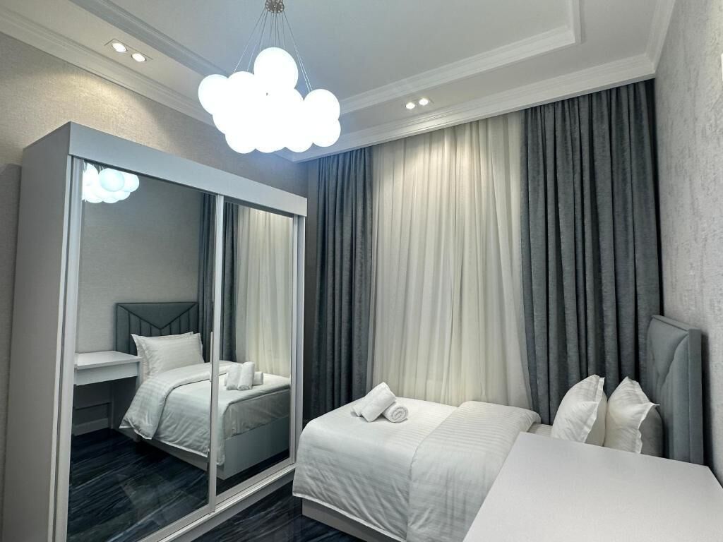 A hotel room with a bed, a wardrobe, and a large mirror.