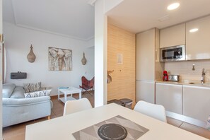Un appartement moderne comprenant un espace de vie, une table à manger, une cuisine équipée d’un four à micro-ondes et un canapé.