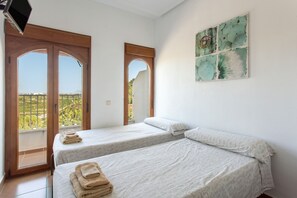 A room with two beds, a TV, and a view of greenery through the windows. - Apartment 'Casa De Panorama' with Lake View, Wi-Fi and Air Conditioning (Xeresa)