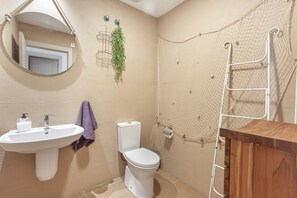 Ein Badezimmer mit Waschbecken, Toilette und Duschbereich mit einer Leiter.