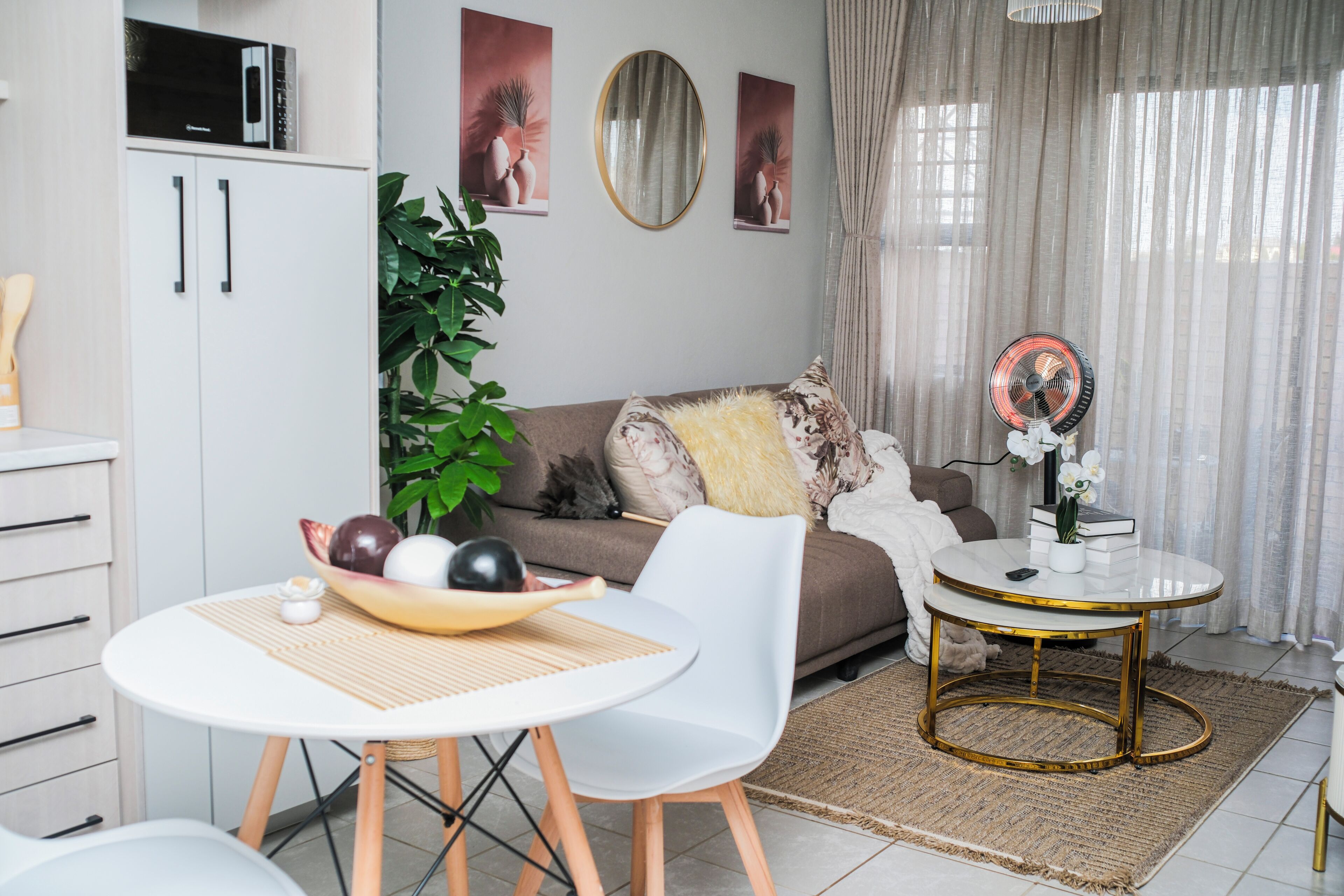 Un salon moderne comprenant un coin repas, un canapé, une table basse et une petite table d’appoint avec un ventilateur.