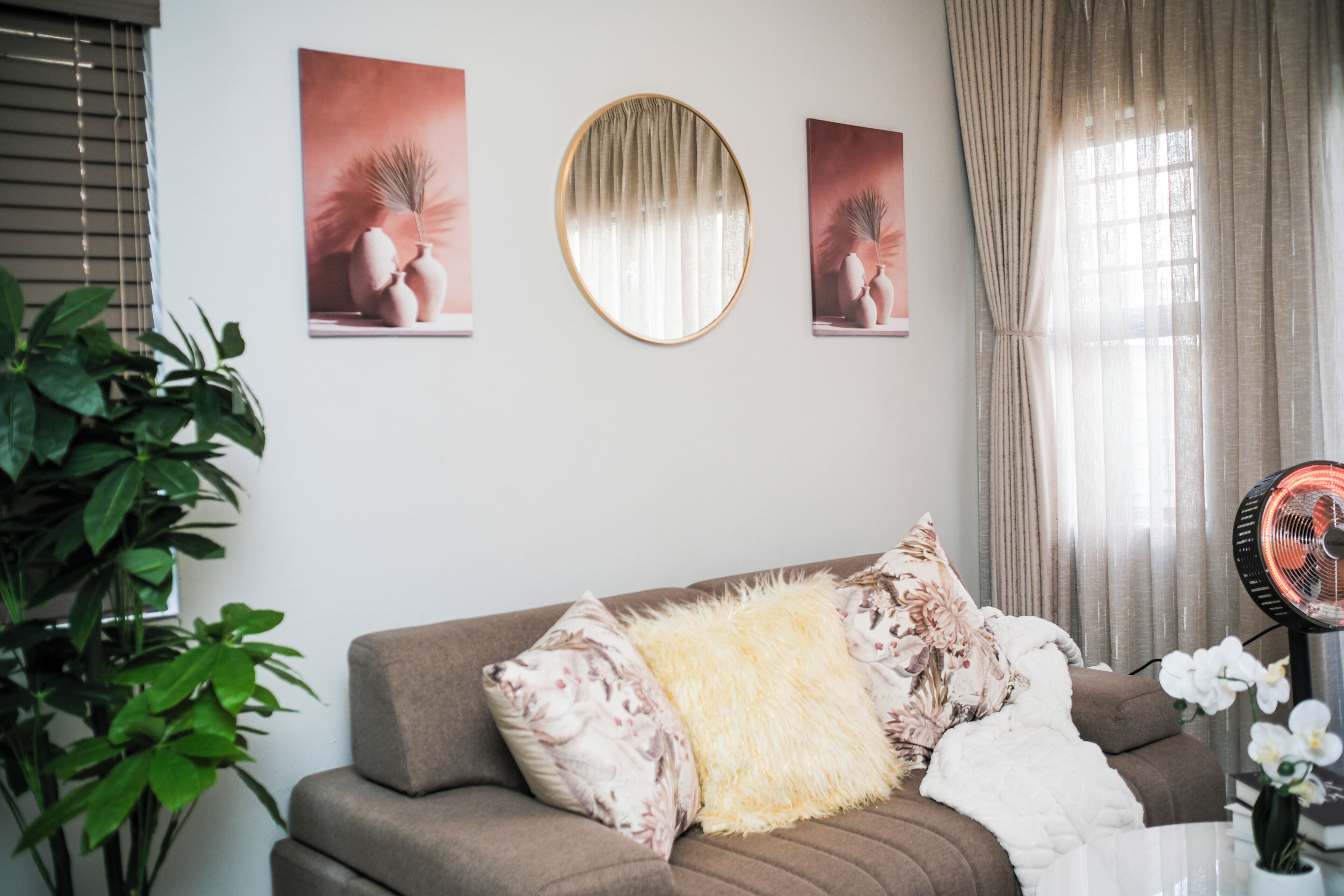 Un salon avec un canapé, un miroir rond et trois tableaux encadrés accrochés au mur.