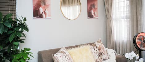 A living room with a sofa, a round mirror, and three framed pictures on the wall.