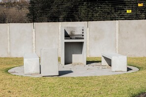 Eine Betonbank und ein Mülleimer in einer Parkanlage.