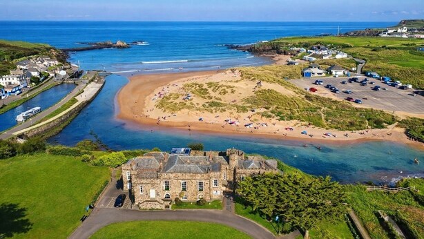 Uma vila costeira com praia, um edifício de pedra e um porto de iates.