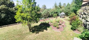 A garden with a gazebo, various plants, and a stone wall. - Gite du Petit Bois: a quiet spot where you can enjoy the sounds of cicadas and birdsong (Gravières)