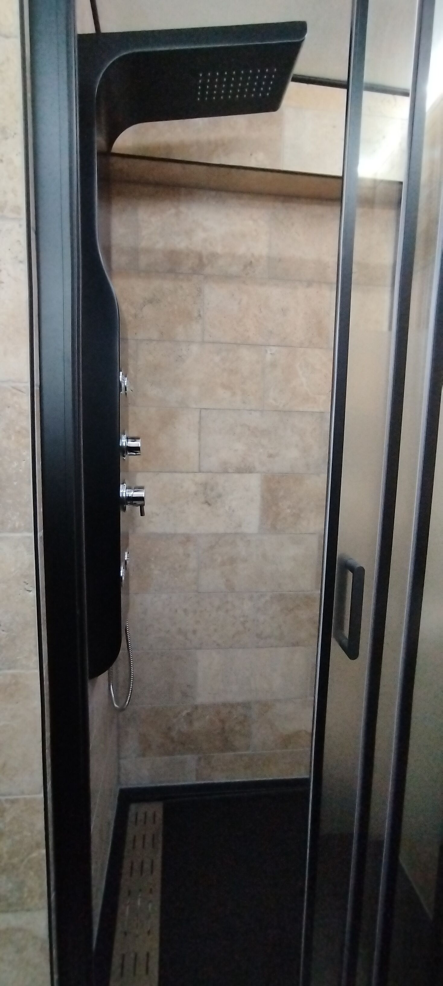 Un baño con ducha, paredes de azulejos y una puerta.