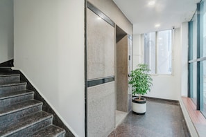 Un interior moderno con una escalera, una planta en maceta y un ventanal.
