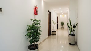 A hallway with a fire extinguisher mounted on the wall, potted plants, and a sign indicating the 3rd floor.