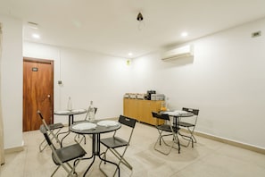 A conference room with a wooden door, a white air conditioning unit, a cabinet with kitchen appliances, and foldable chairs. - Rcc Hotels Pride Kukatpally (Hyderabad)