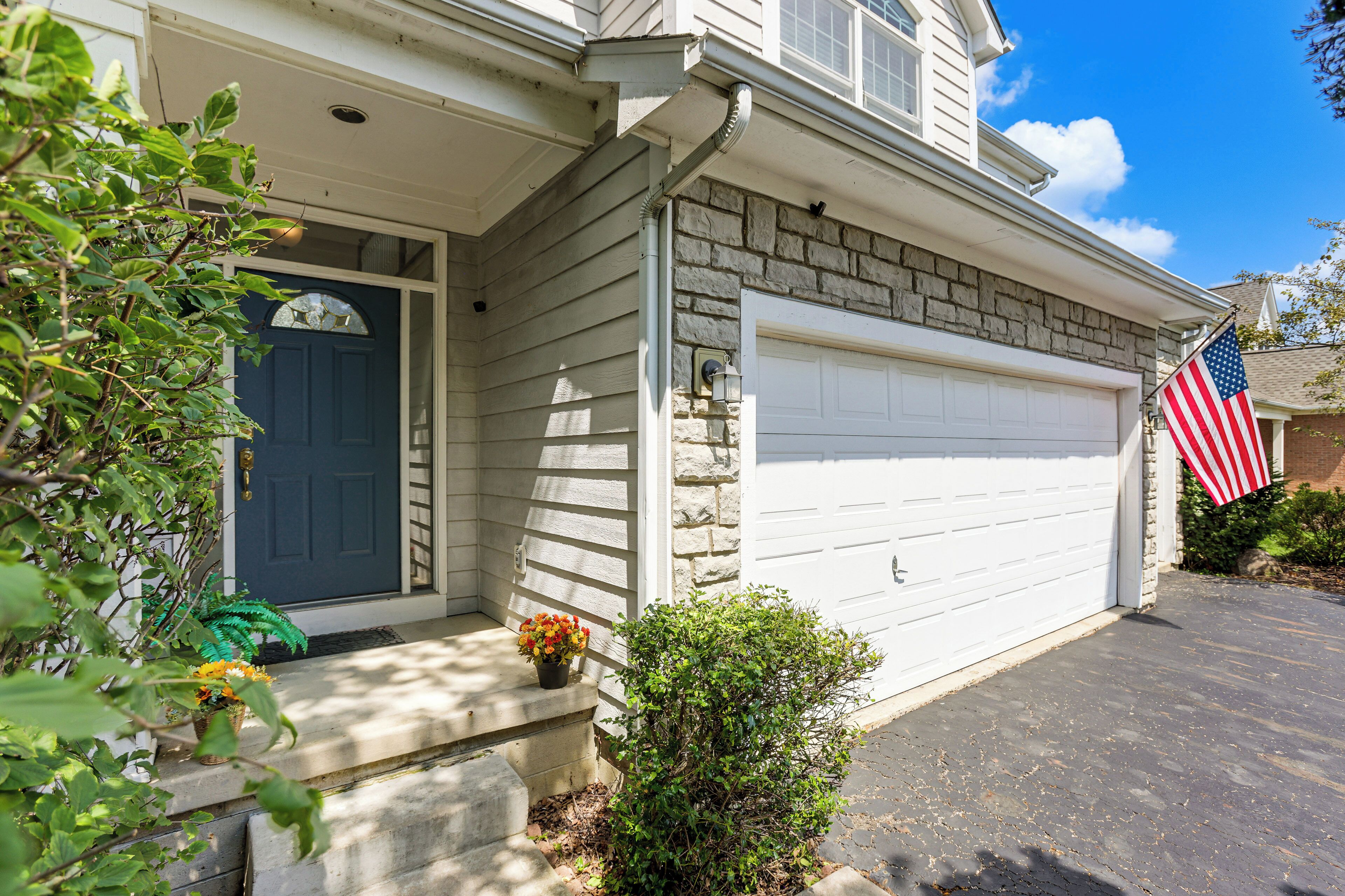 A residential garage with a white door and an American flag.