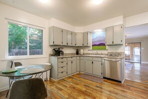 A compact kitchen with a dining area, a refrigerator, and a coffee maker. - The Sugar Shack - Central Loveland Home w/ Patio (Loveland)