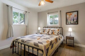 A bedroom with a bed, two bedside lamps, a ceiling fan, and a painting on the wall. - The Sugar Shack - Central Loveland Home w/ Patio (Loveland)