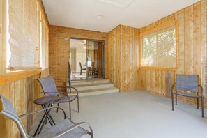 A room with a brick wall, wooden paneling, a ceiling fan, and a view through a glass door. - The Sugar Shack - Central Loveland Home w/ Patio (Loveland)