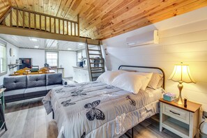 A bedroom with a bed, a nightstand, a desk, a sofa, and a staircase leading to an upper level. - 2 Hot Tubs, Games & BBQs! Henagar Group Retreat (Henagar)
