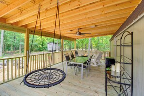 A covered outdoor deck with a table and chairs, a hanging swing, and a railing. - 2 Hot Tubs, Games & BBQs! Henagar Group Retreat (Henagar)