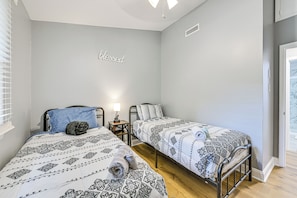 A room with two single beds, a bedside table with a lamp, and a wall with a 'blessed' sign. - Centrally Located Charlotte Home w/ Patio & Yard! (Charlotte)