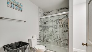Ein modernes Badezimmer mit Duschkabine aus Glas, Toilette und Mülleimer.