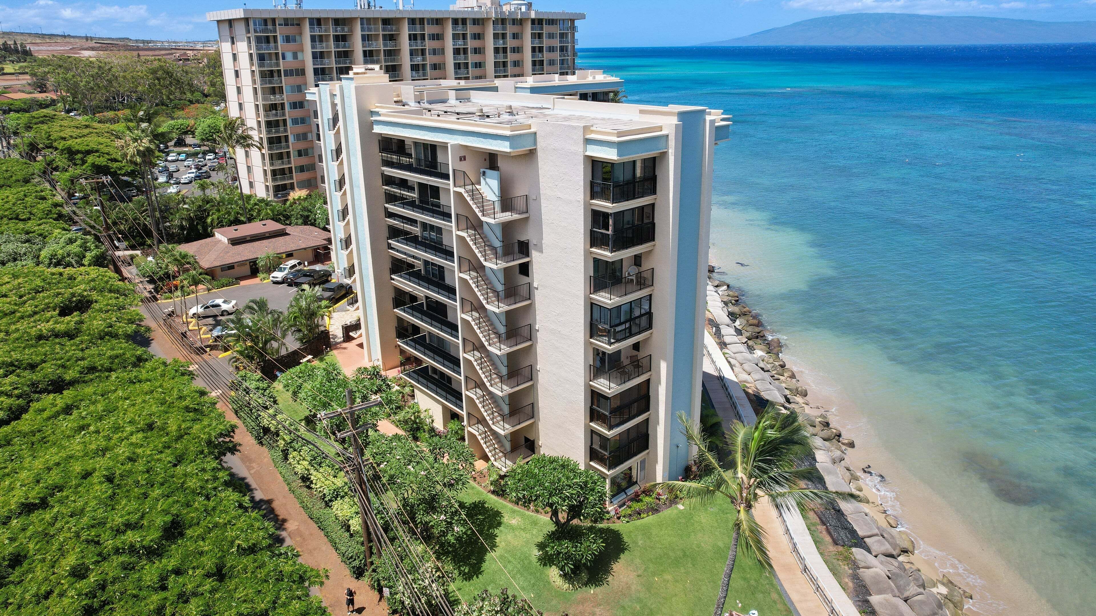 A multi-story hotel with balconies overlooking a beach and ocean.