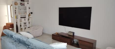 Ein modernes Wohnzimmer mit einem hellblauen Sofa, einem weißen Sitzsack, einem Flachbildfernseher und einer Holz-Unterhaltungseinheit.