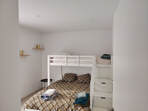 A bunk bed with a patterned bedspread, a bedside table, and a wardrobe with drawers. - Villa with a pool, sleeps 6 to 7 people (Thuir)