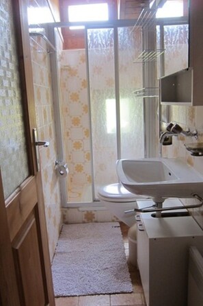 Un baño con inodoro, lavamanos y zona de ducha.