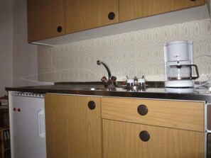 A kitchen with wooden cabinets, a coffee maker, and a dishwasher.