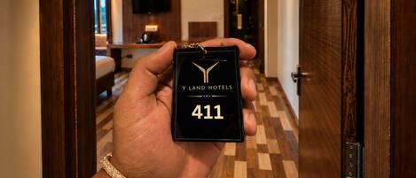 Egy kéz, amelyben egy fekete színű kulcstartó van, rajta a „Y LAND HOTELS” felirattal és a „411” számmal.