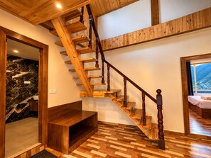 Un escalier en bois, un mur en marbre et un lit avec vue sur la montagne.
