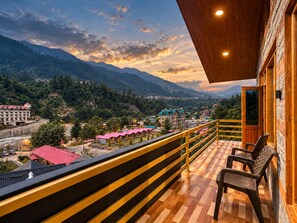 A balcony with a view of a mountainous landscape, wooden railings, and a checkered floor.