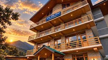 A multi-story hotel with a wooden facade, balconies, and a mountain backdrop.
