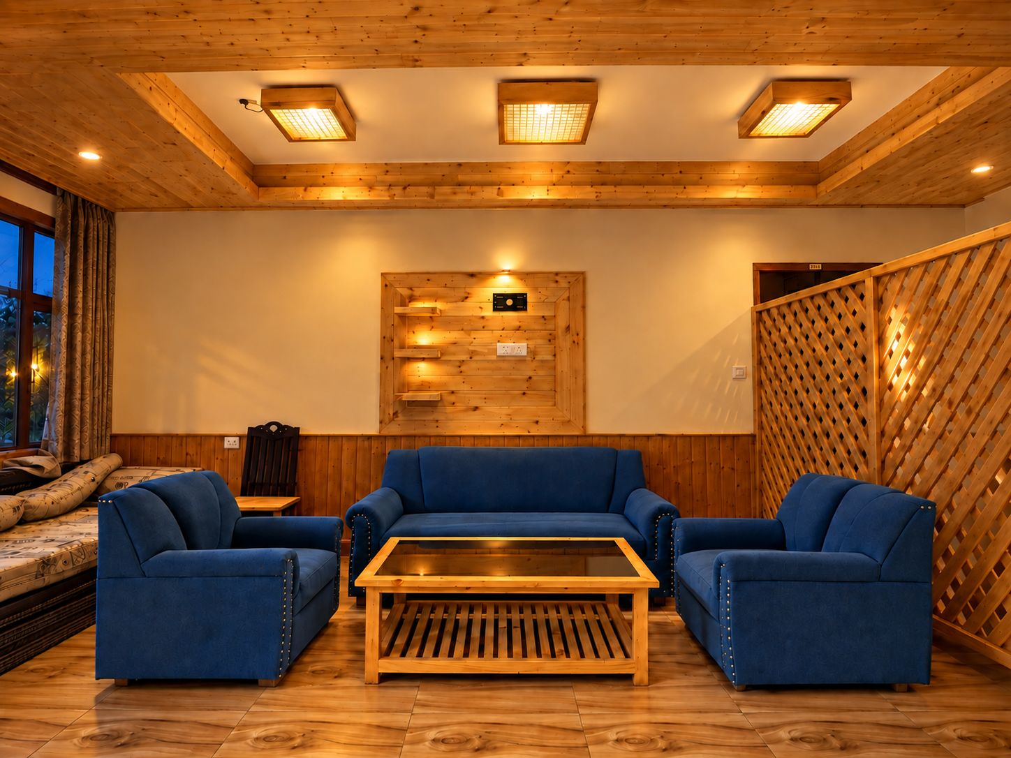 Una stanza con travi in legno al soffitto, un pannello di legno a parete con una radio montata e un divano blu.
